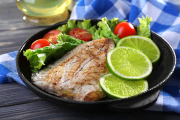 Dish of fish fillet with salad and lime on table close up