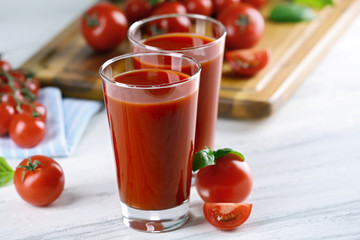 Glasses of tomato juice with vegetables on wooden table close up