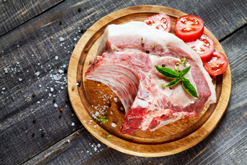 Raw meat ribs bone steak, pork with basil and tomatoes on a cutt