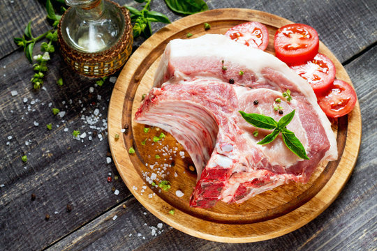 Raw meat ribs bone steak, pork with basil, oil and tomatoes