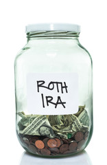 Glass jar with with a white ROTH IRA label and some money in it