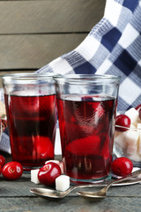 Glasses of sweet homemade cherry compote on table on wooden background