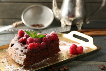 Piece of cake with Chocolate Glaze and raspberries on tray on wooden background