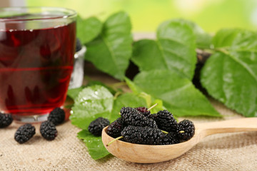 Glass of refreshing mulberry juice with berries on table close up