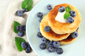 Fritters of cottage cheese with blueberries in plate, closeup