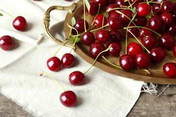 Cherries on tray, on wooden background