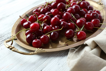Cherries on tray, on wooden background