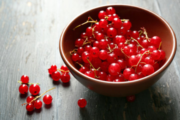 Ripe red currant  in bowl on wooden background
