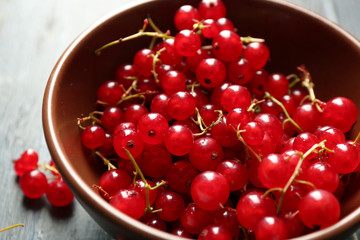 Ripe red currant  in bowl on wooden background