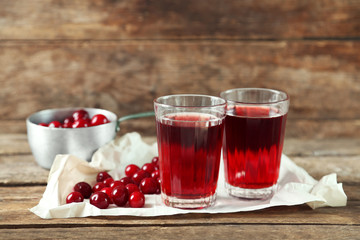 Two glasses with cherry juice on table, on wooden background