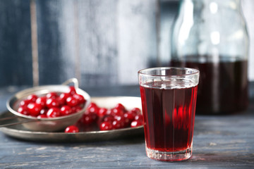 Sweet homemade cherry juice on table, on color wooden background