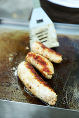 Sausages cooking in frying pan close up