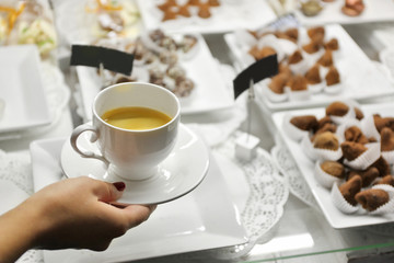 Female hand holding cup of coffee on table background
