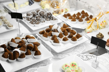 Delicious chocolate candies on plates on table close up