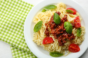 Spaghetti Bolognese on white plate, on color wooden background