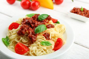 Spaghetti Bolognese on white plate, on color wooden background