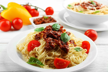 Spaghetti Bolognese on white plate, on color wooden background