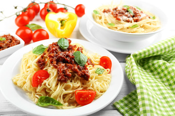 Spaghetti Bolognese on white plate, on color wooden background