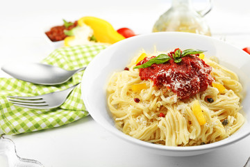 Spaghetti with tomato sauce and cheese on white plate, on color wooden background