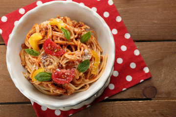 Homemade Spaghetti Bolognese with parmesan cheese in white bowl, on color wooden background