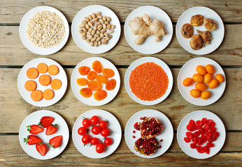 Different products on saucers on wooden table, top view