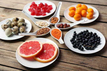 Different products on saucers and spoons on wooden table close up