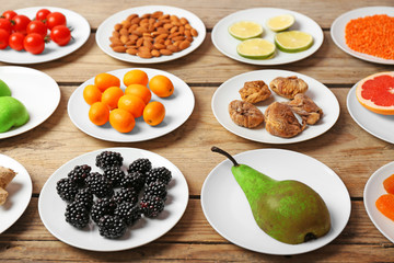Different products on saucers on wooden table close up