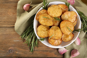 Delicious baked potato with rosemary in bowl on table close up