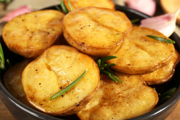 Delicious baked potato with rosemary in bowl close up