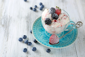 Delicious ice cream with fresh frozen berries, on color wooden background