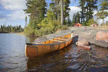 Campsite and canoe on rocky shore of lake