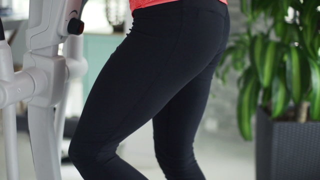 Sexy woman exercising on elliptical machine in the gym
