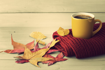 Coffee cup, red scarf and autumn leafs over pale wood