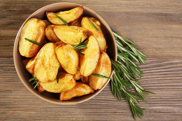 Baked potato wedges on wooden table, top view