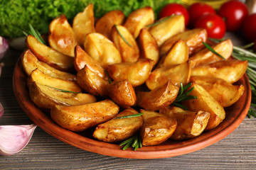 Baked potato wedges on wooden table, closeup