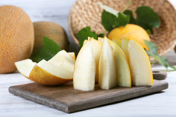Slices of ripe melons with green leaves on table close up