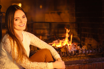 Fototapeta na wymiar Happy woman relaxing at fireplace. Winter home.