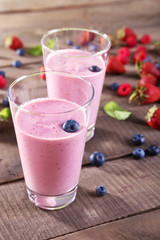 Glasses of berry smoothie on wooden table, closeup