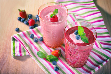 Glasses of berry smoothie on wooden table, closeup