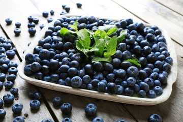 Tasty ripe blueberries with mint on wooden table close up