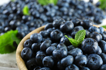 Tasty ripe blueberries with mint in bowl on table close up