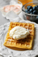 Sweet homemade waffles on plate, on color wooden background