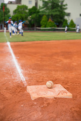 baseball and base on baseball field with players practising on background © Freer