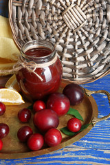 Tasty homemade plum jam in glass jar on metal tray, closeup
