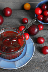 Tasty homemade plum jam on wooden background