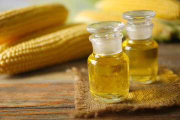 Fresh corn with bottles of oil on table close up