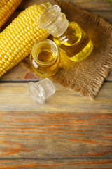 Fresh corn with bottles of oil on table close up