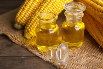 Fresh corn with bottles of oil on table close up