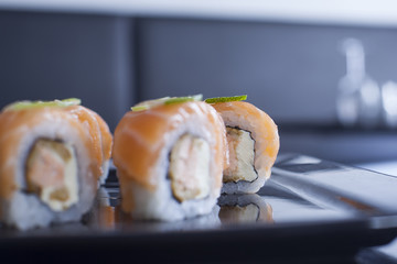 Sushi roll with cream cheese and fried salmon. Topped with raw s