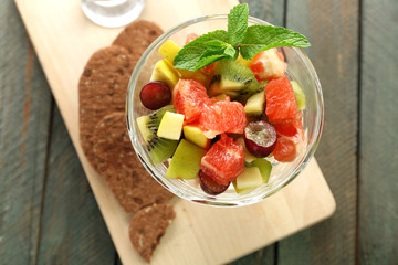 Fruit salad in glass bowl, on wooden background